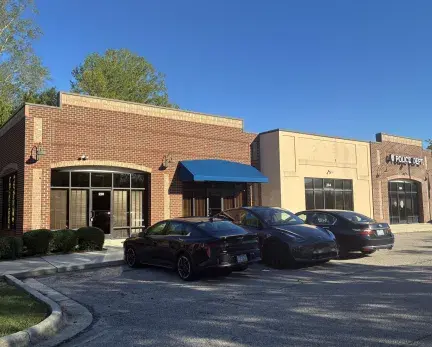 A brick building with three different front door entrances. The right building is labeled the Police Department.