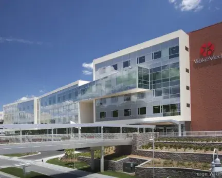 Hospital with glass exterior with white frame and red brick on the side.