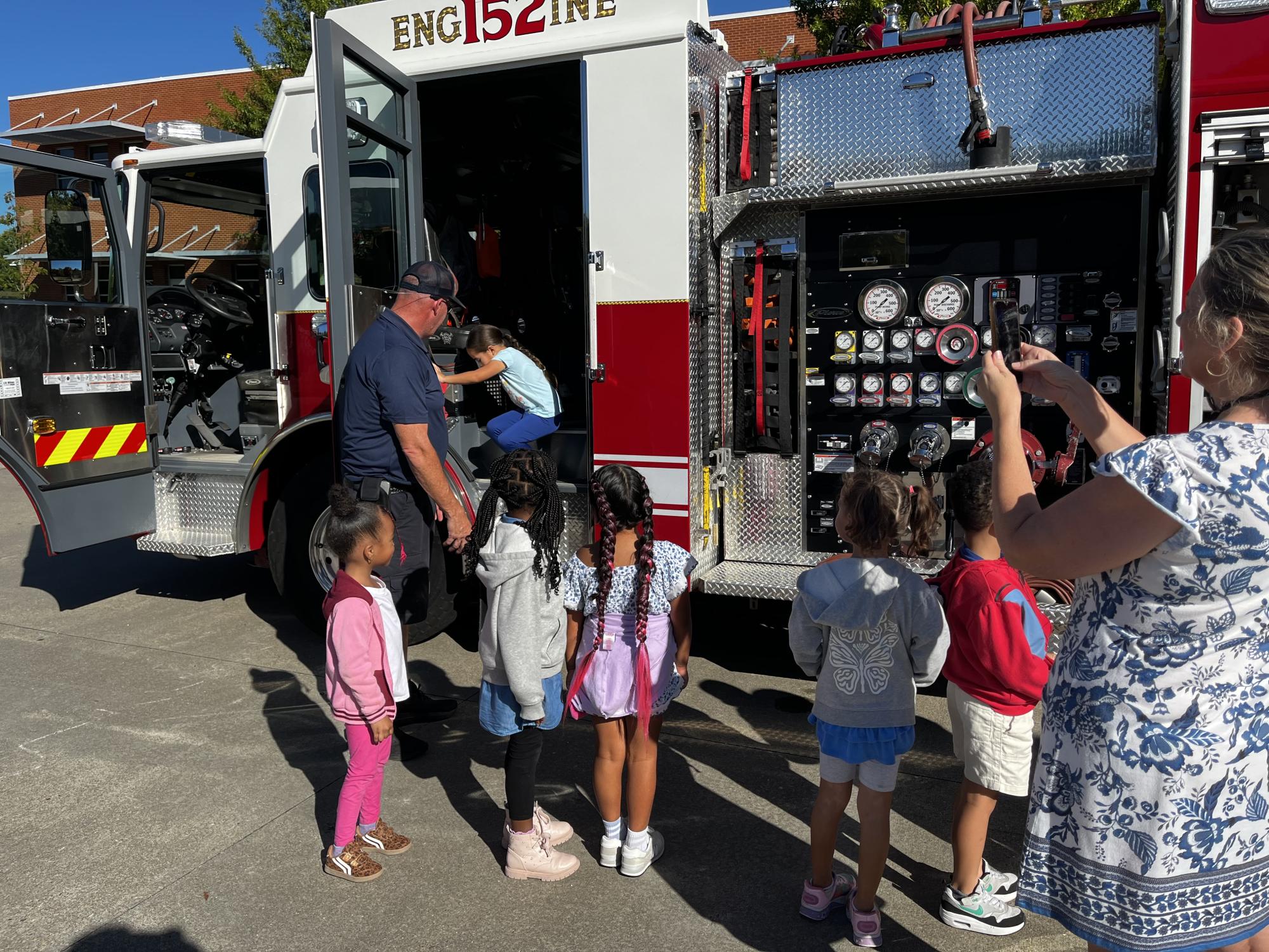 Children exploring the side of a firetruck 