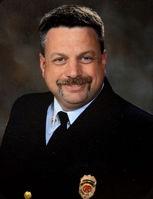 Man sitting in front of a navy background with a black suite
